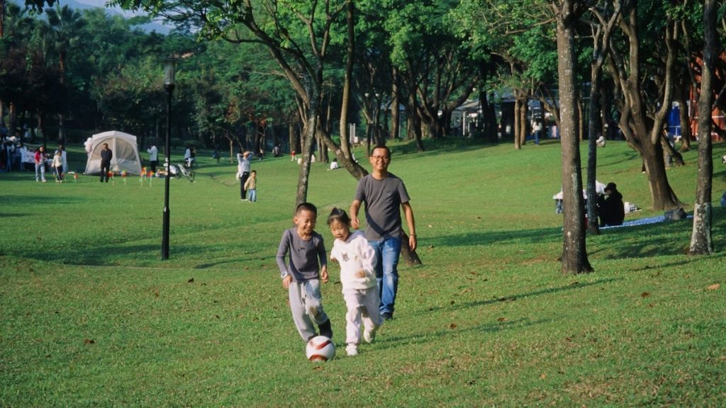 A group of people walking across a lush green park
